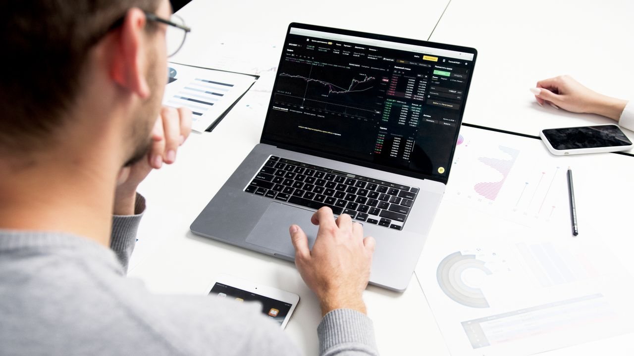 Person at a white desk using a laptop with a trading platform open, choosing an order type