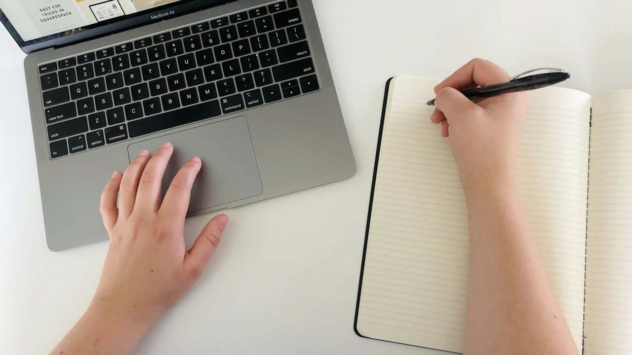Person writing a one-page trading plan in a notebook, the first step in how to create a trading plan