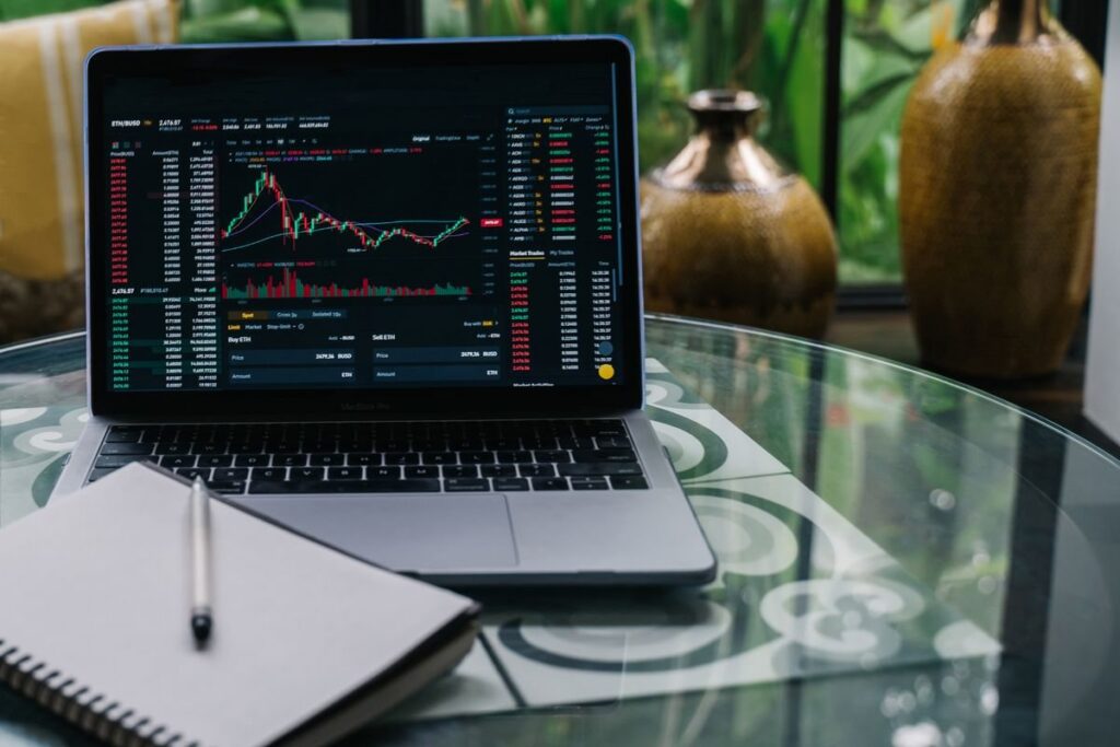 Laptop on a kitchen table showing a trading platform chart where a falling wedge is forming