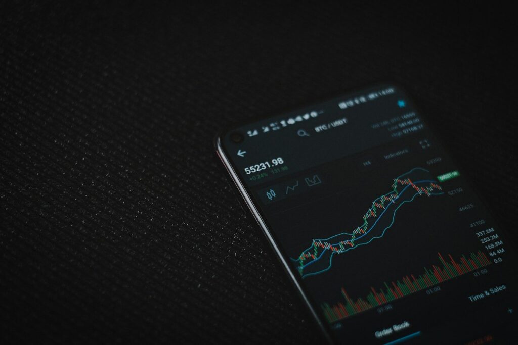 Phone showing a trading app chart on a dark surface