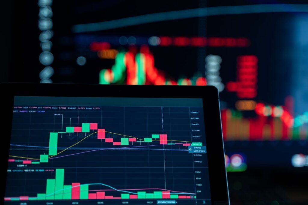 Tablet showing a candlestick and volume chart in front of glowing screens