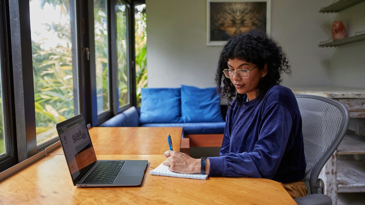 Trader at a home desk with a laptop and notebook, planning rules for trading with a small account