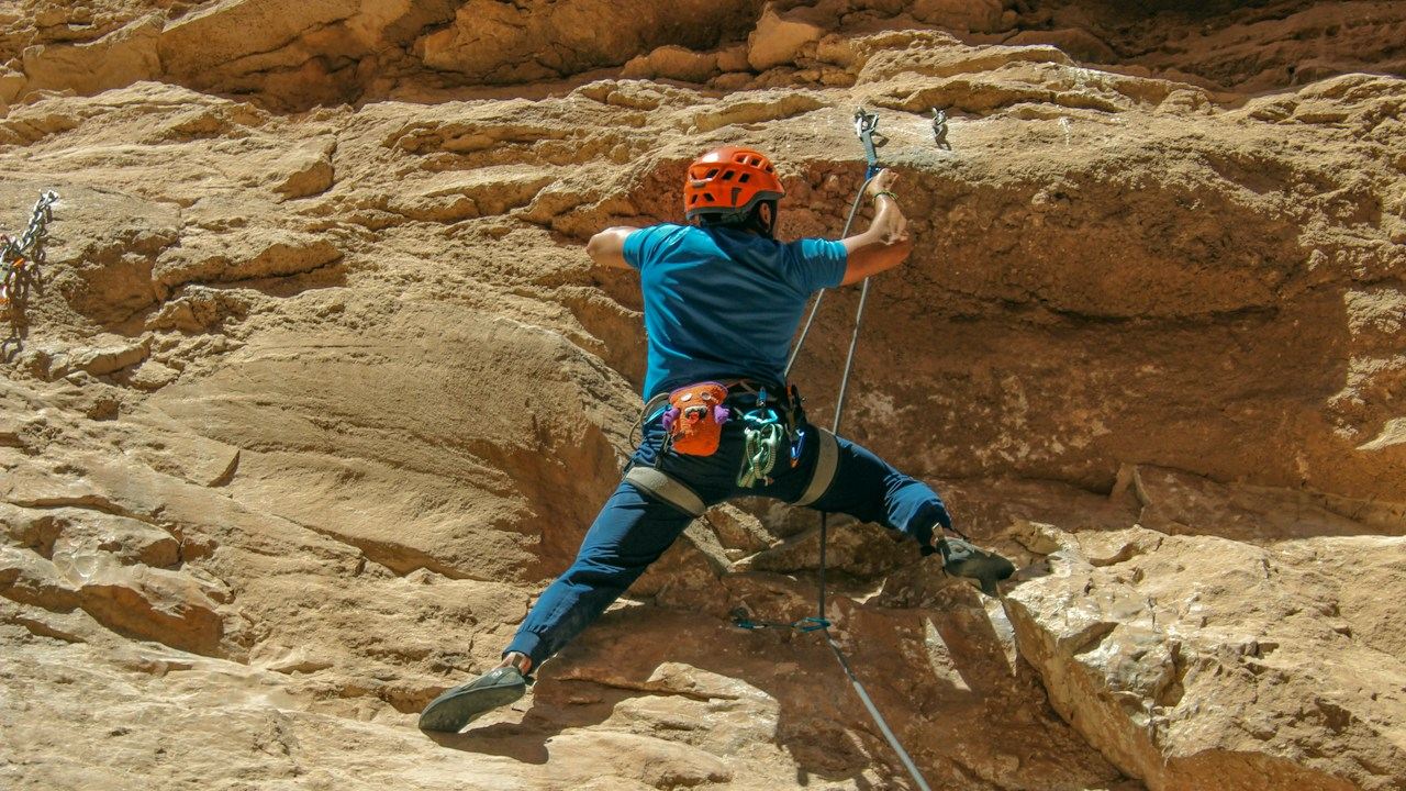 Climber on a sandstone rock face with a rope, like a trailing stop locking in progress as a trade moves up