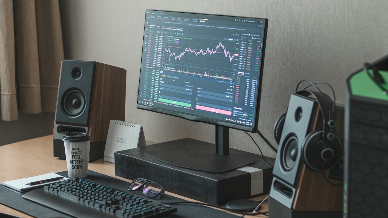 Desk with a monitor showing a price chart between two speakers