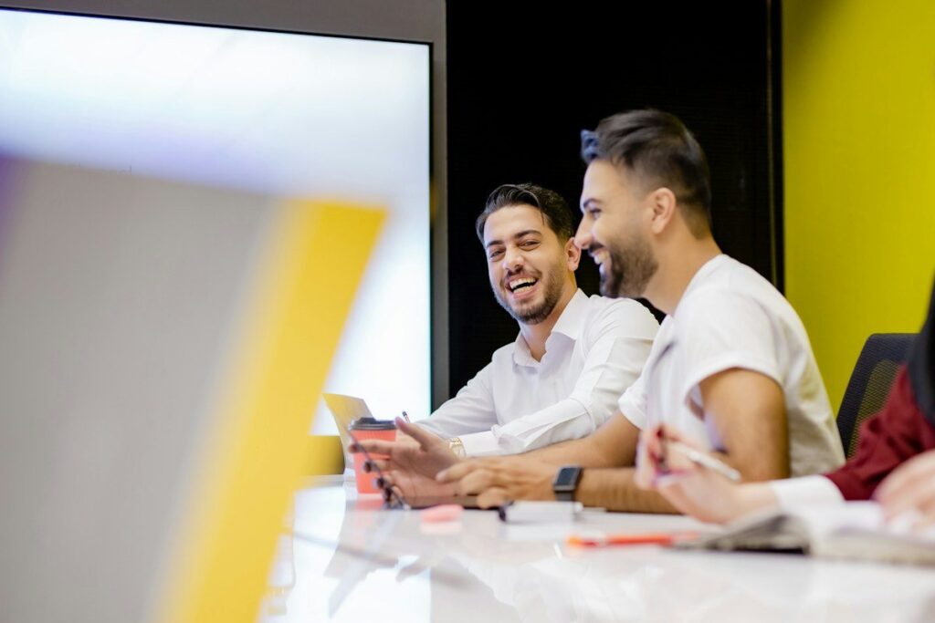 Two colleagues laughing at a meeting table