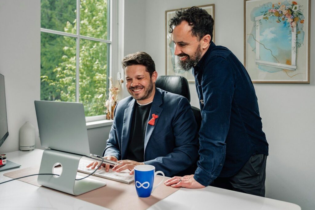 Two colleagues smiling at a computer screen in an office