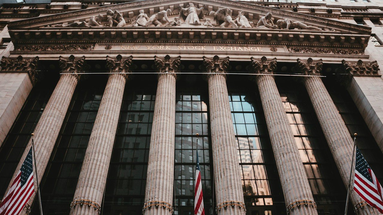 New York Stock Exchange building with flags, home of the shares behind the US500 index traders follow from the UK