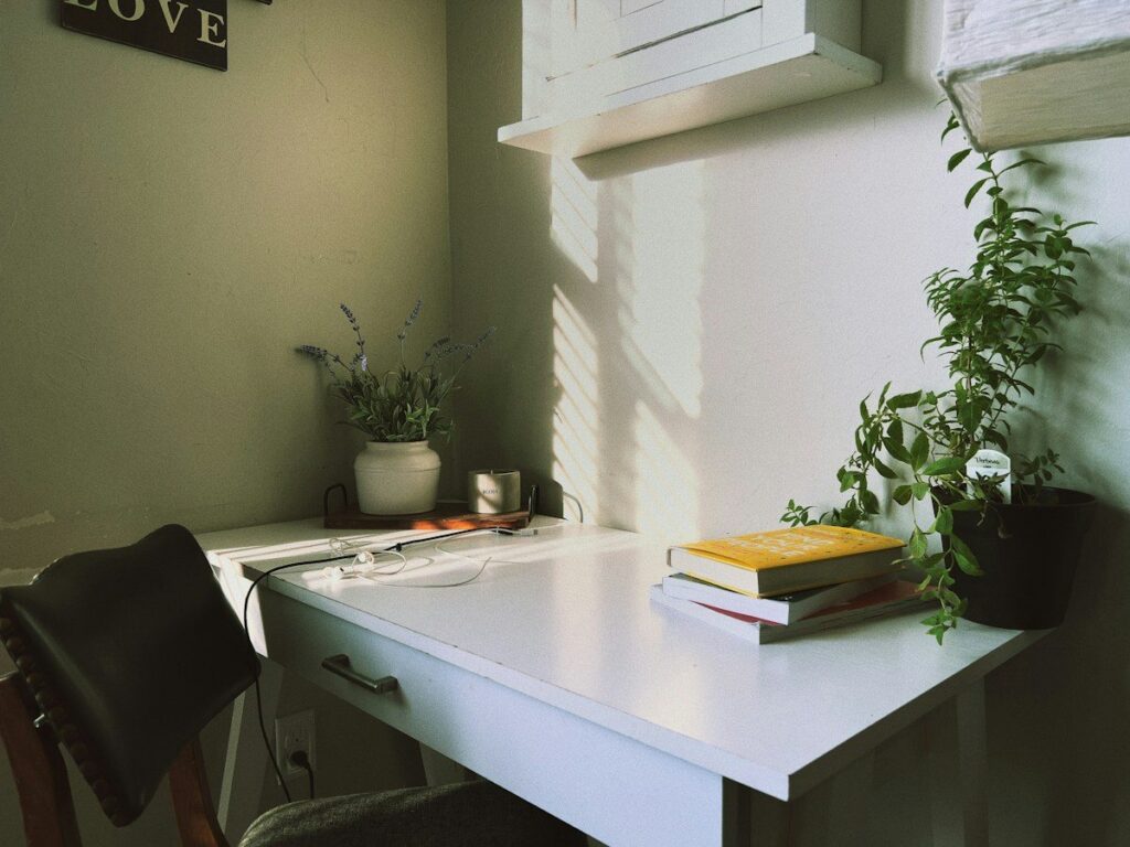 Sunlit home office desk with books, a reminder of the limited weekly hours a part-time trader has to learn