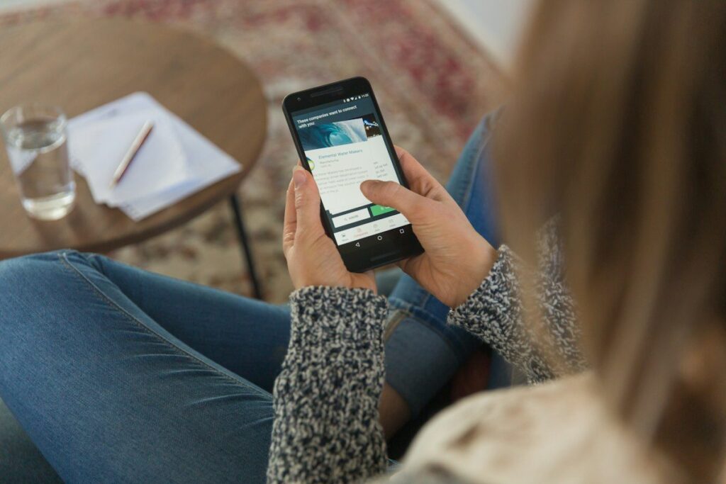 Person at home holding a phone with a trading app open