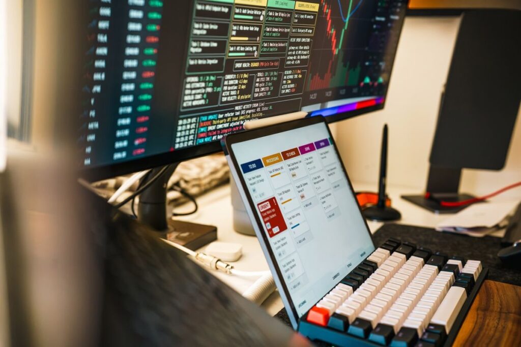 Tablet showing a trading platform in front of a monitor of prices