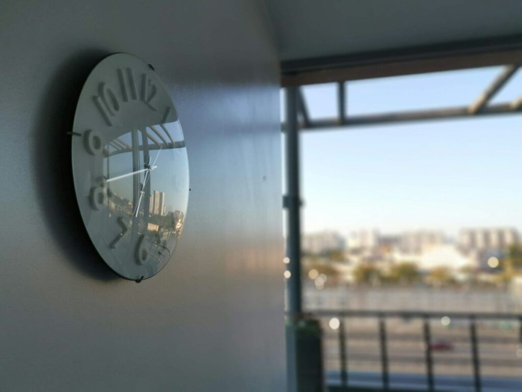 Wall clock in an office beside a window with a city view